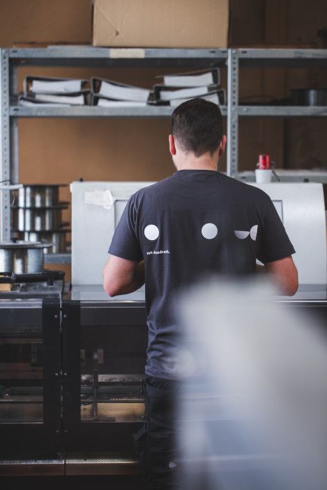 Mitarbeiter in der Endfertigung vor dem Sammelhefter